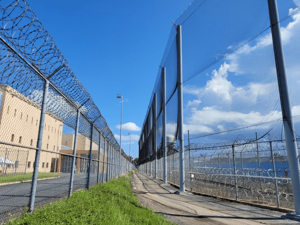 High-security perimeter netting with razor wire fencing at a correctional facility