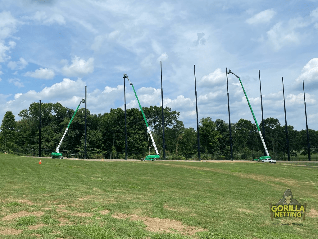 Professional installation of tall driving range netting poles by Gorilla Netting crews using boom lifts